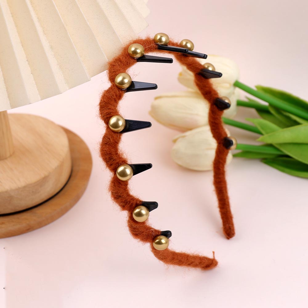 Decorative headband with brown fuzzy band, gold beads, and black clips on a light pink surface with tulips.