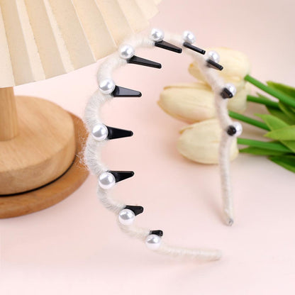 Hairband with black spikes and pearls on a light pink background with tulips.