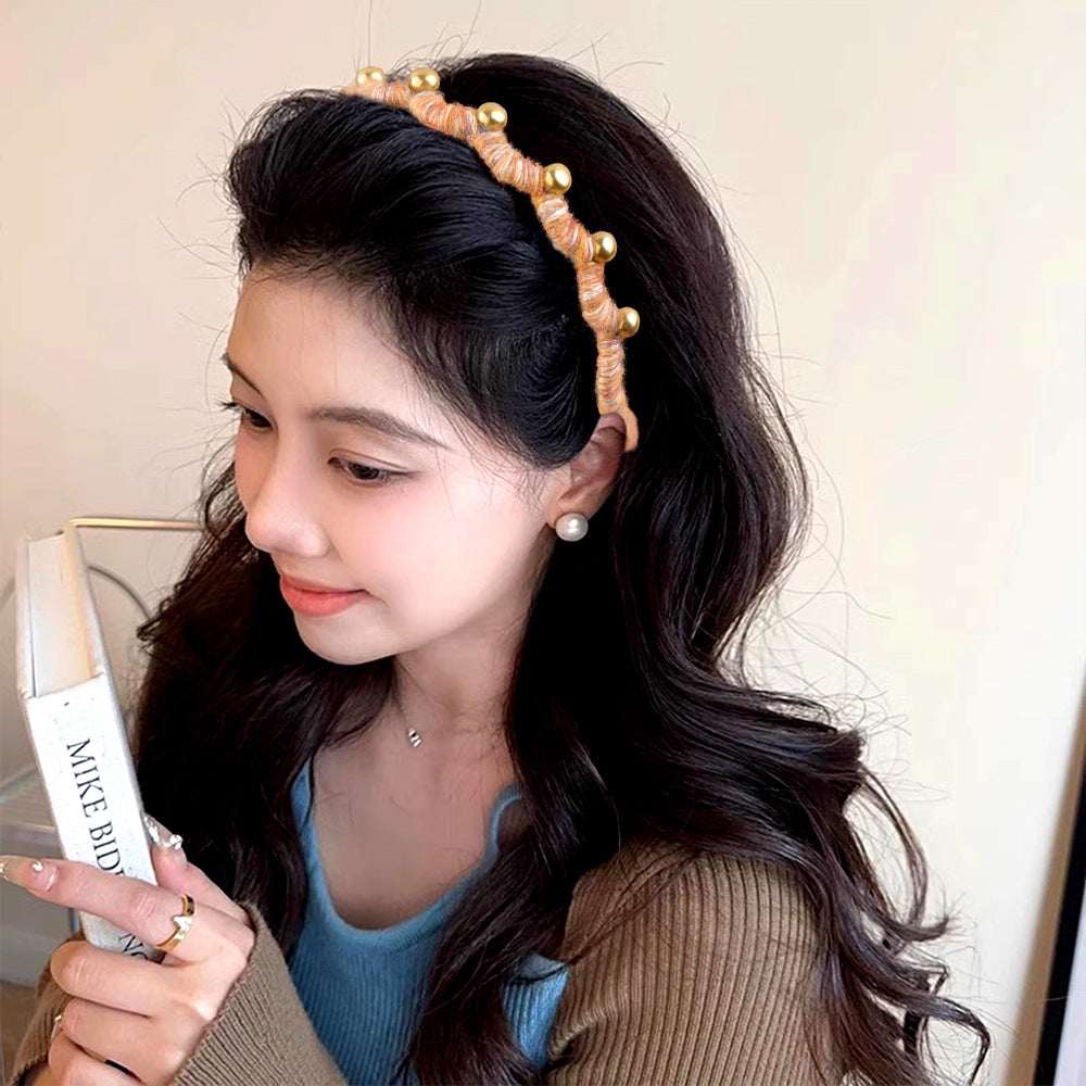 Woman wearing a decorative headband holding a hair straightener.